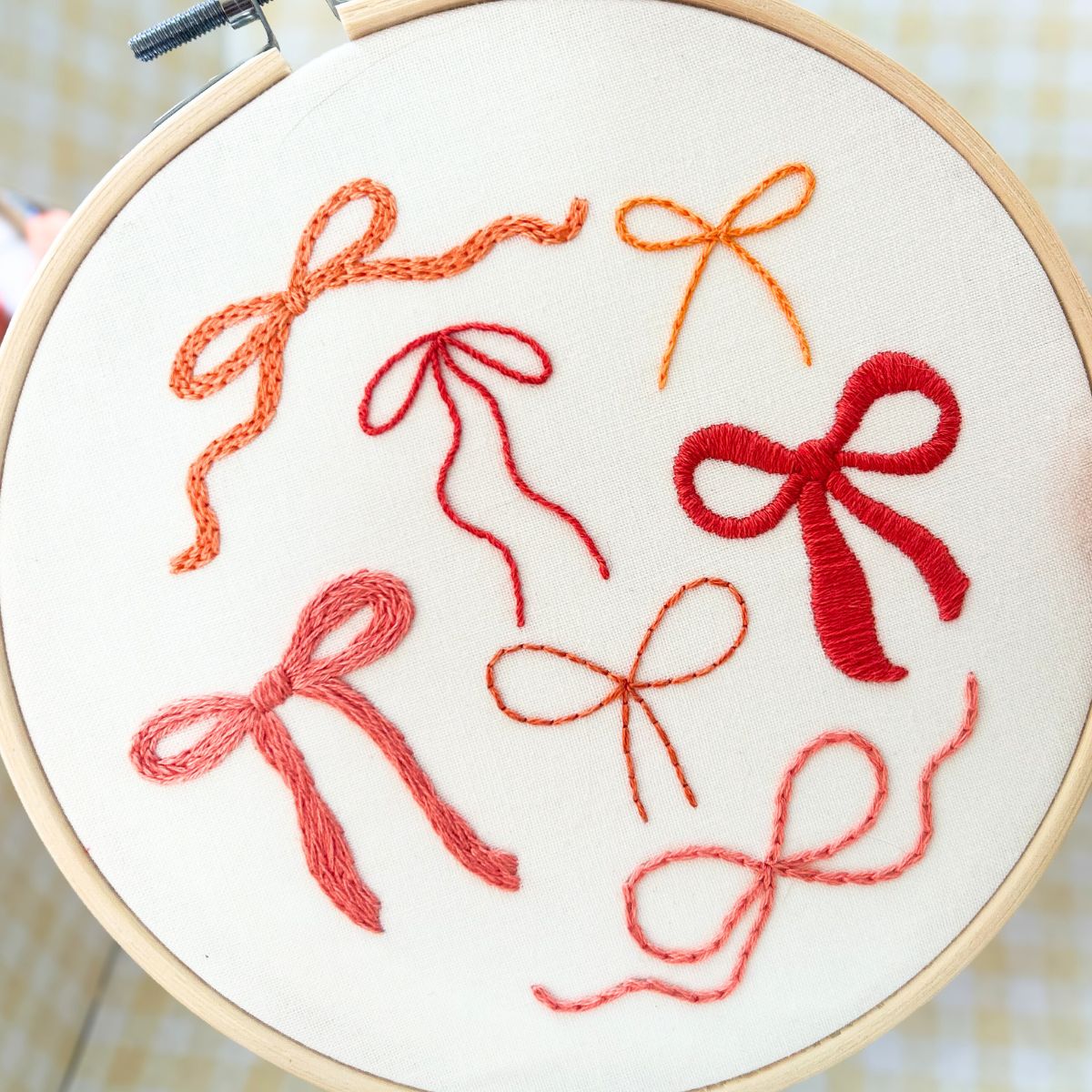 an embroidery hoop with 7 different bows stitched to it